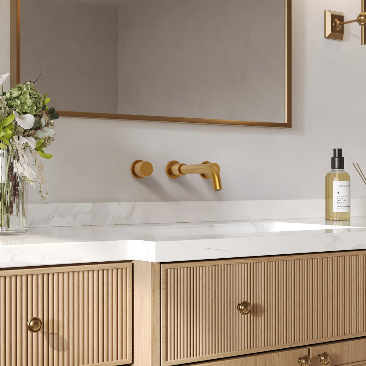 Wall-mounted brass faucet with separate handles above a bathroom vanity